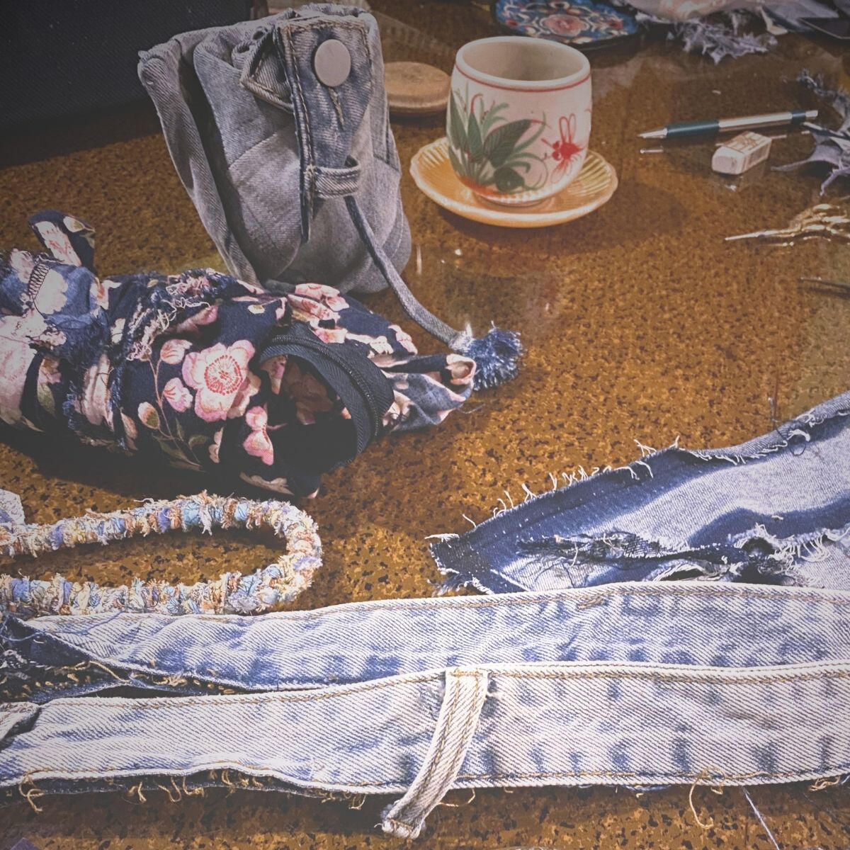 Disassembled denim garment pieces and folded tote bag on a work table.