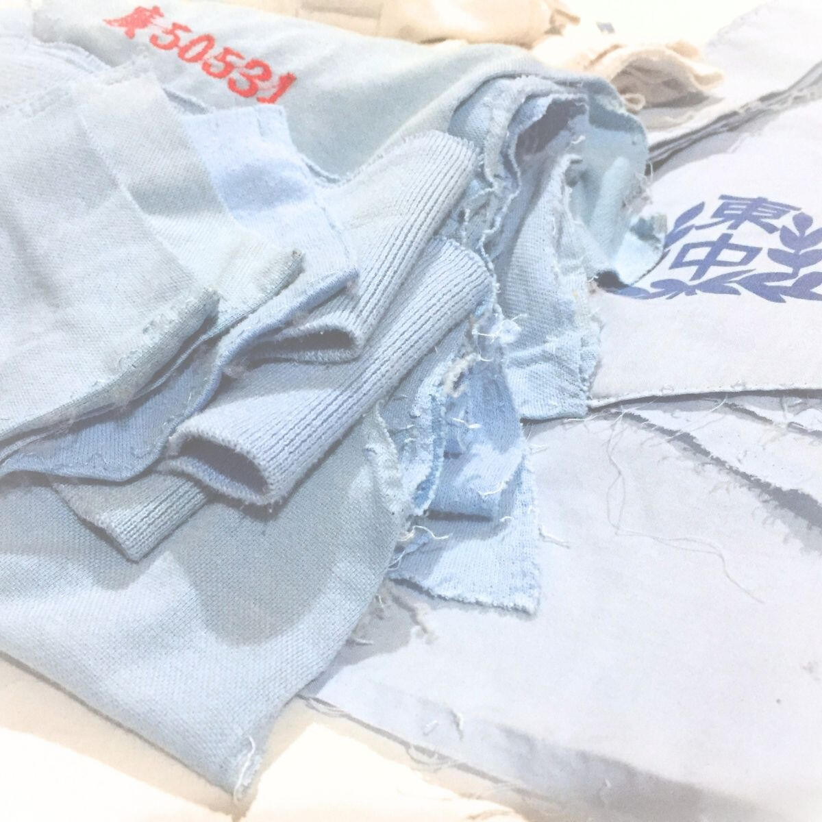 School badges, student numbers, and fabric panels from deconstructed uniforms.