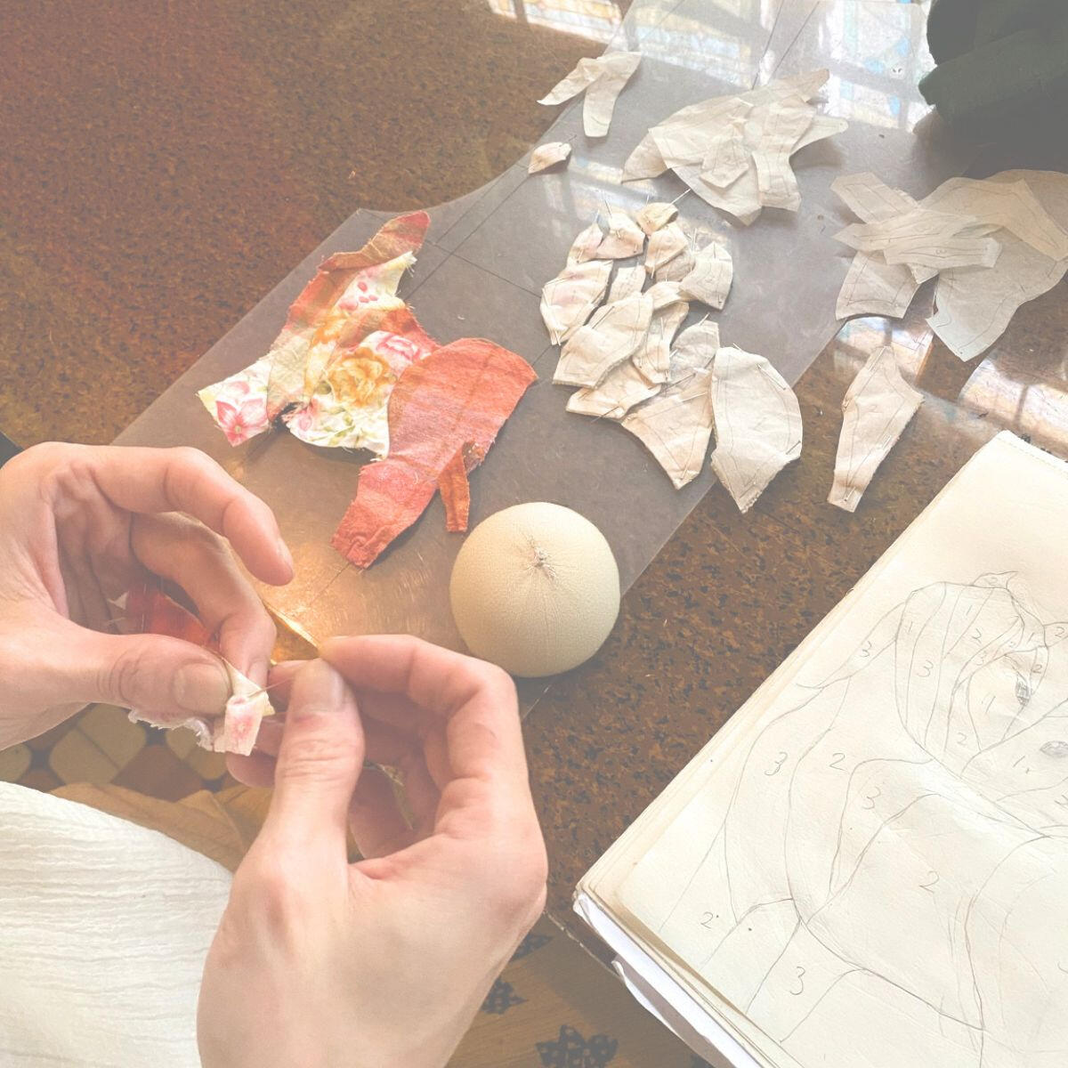 Hand positioning textile fragments over pattern pieces during the construction of Walking Together.