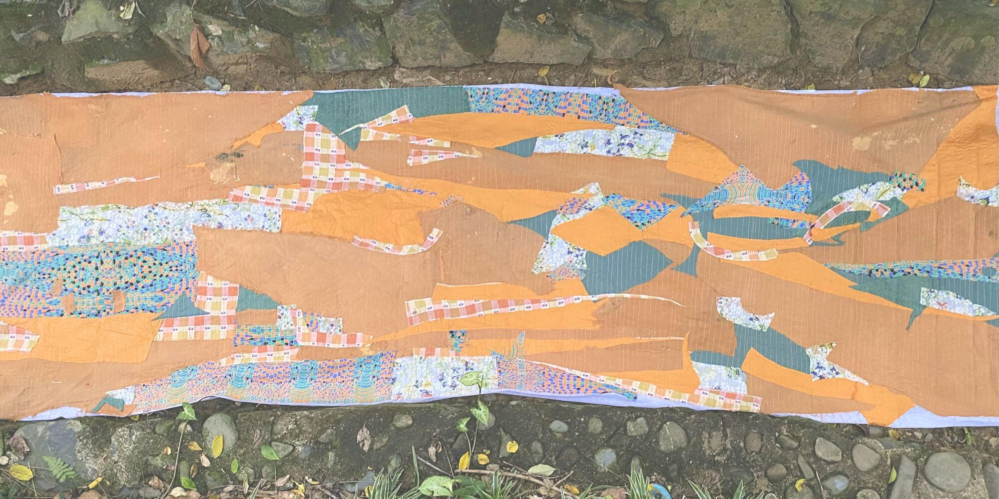 Textile installation laid among stone paving outdoors.
